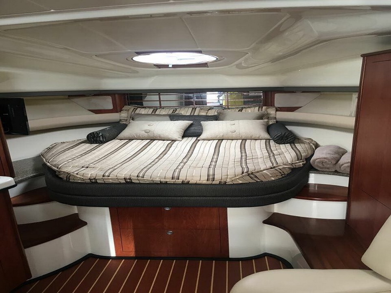 Mid-cabin double bed of the Monterey sport yacht with striped bedding and skylight, cozy sleeping space for overnight Cancun cruises