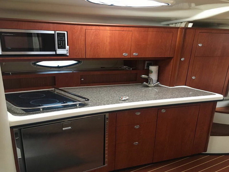 Galley of the Monterey yacht with wood cabinets, microwave, cooktop and fridge, fully equipped for day outings from Cancun