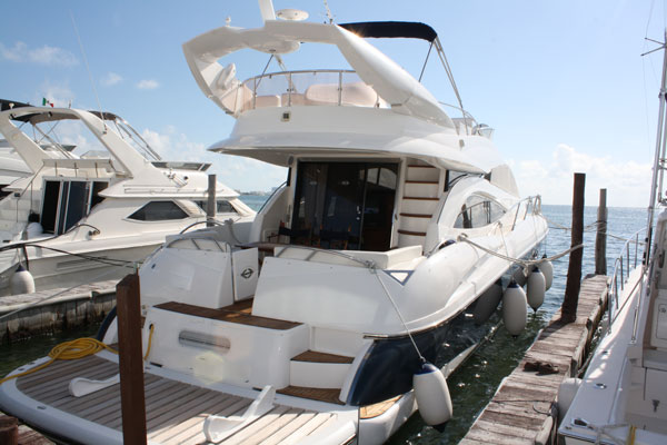 Stern view of Sunseeker 58 ft luxury yacht at Cancún marina dock with flybridge, teak swim deck and fenders