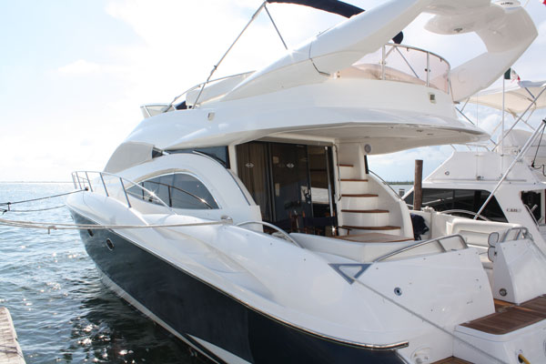 Stern deck of Sunseeker 58 ft flybridge charter yacht at Cancún marina showing cockpit, boarding stairs and teak deck