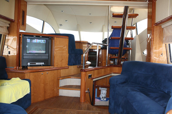 yacht rental with navy blue sofas, TV entertainment unit, mahogany trim and stairs to flybridge