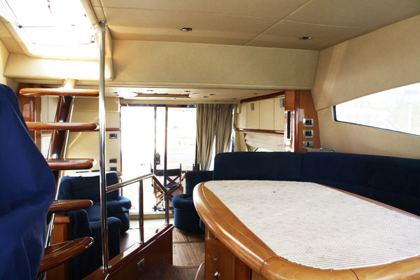 Main salon of Sunseeker 58 ft flybridge yacht with navy seating, dining table, wood staircase and natural Caribbean light