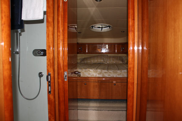 Doorway view through Sunseeker 58 ft yacht showing shower stall and forward stateroom with bed and porthole window