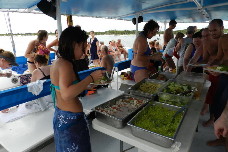 Guests swimming and snorkeling near Raiatea catamaran in turquoise Caribbean sea Riviera Maya day tour