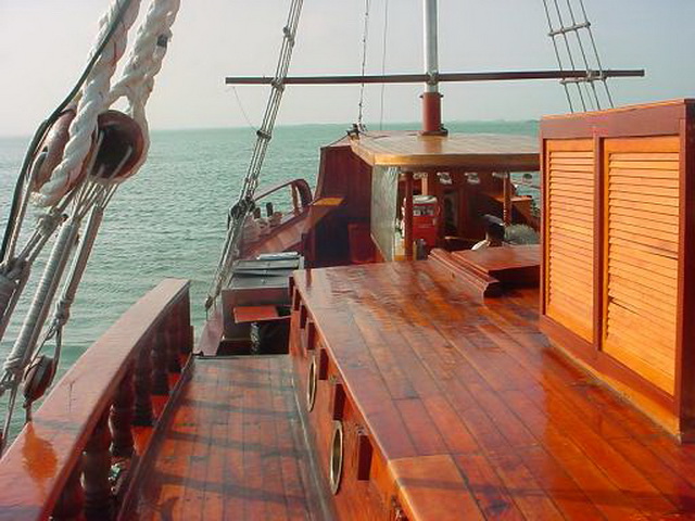 Polished wooden main deck of the Columbus galleon with bench seating and rigging, open to lagoon views in Cancun