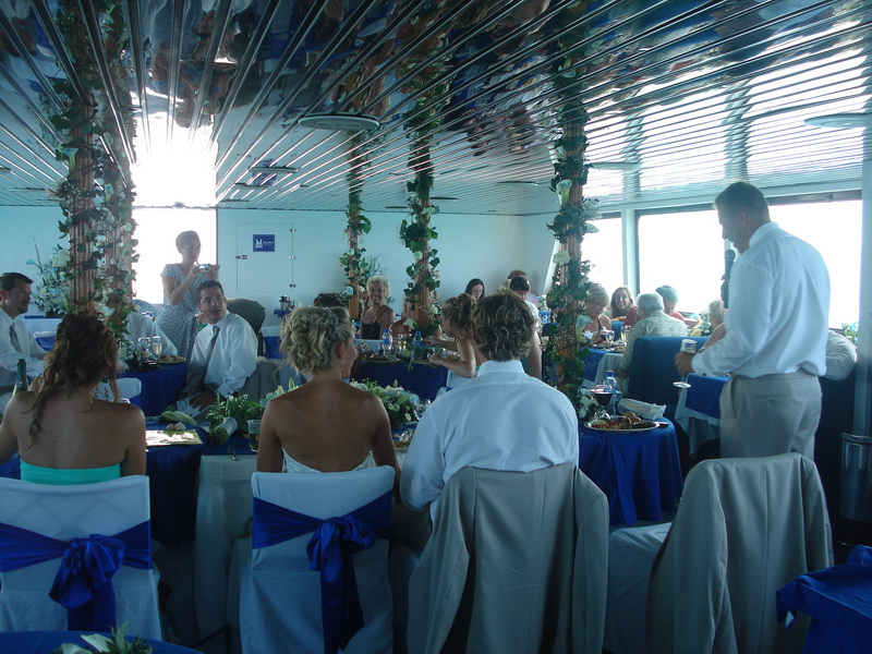 Elegant wedding reception tables dressed in blue and white linens set up aboard an event boat in Cancun