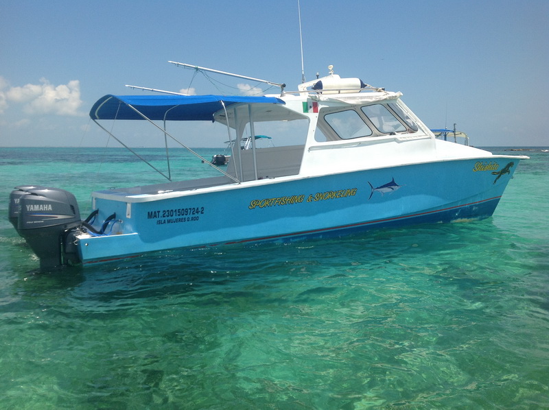 Private boat moored at the Isla Mujeres downtown pier beside waterfront restaurants