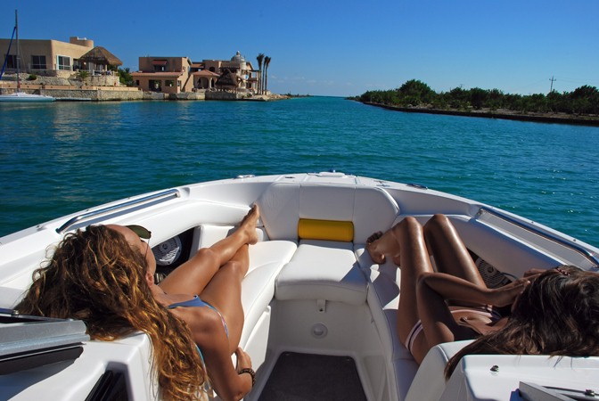 View from bow of Regal sport boat cruising through blue lagoon canal at Puerto Aventuras Riviera Maya private charter