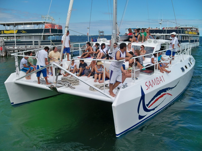 Catamaran Samba 1 at Cancun marina with group of guests on foredeck, white sailing charter catamaran private tour Isla Mujeres